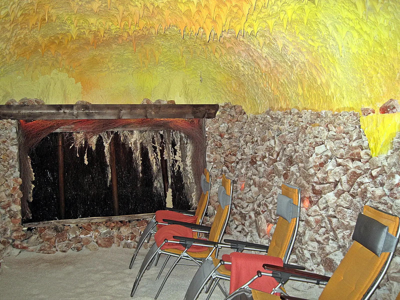Salzgrotte mit Wand aus Salzbrocken und gelb beleuchteter Decke
